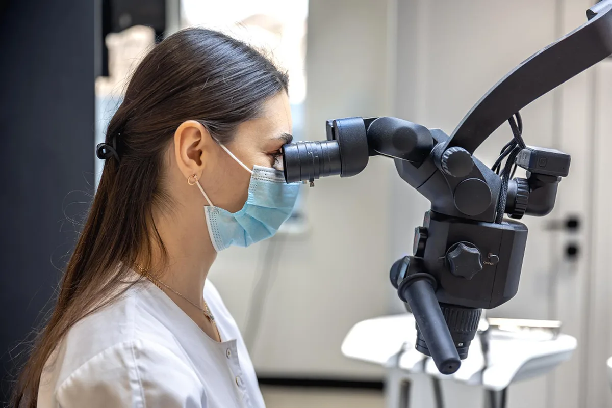 Dentysta przeprowadzający zabieg leczenia kanałowego przy pomocy mikroskopu